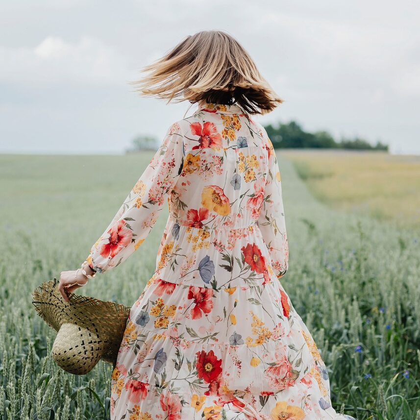 Woman in a floral dress with a woven hat in a field